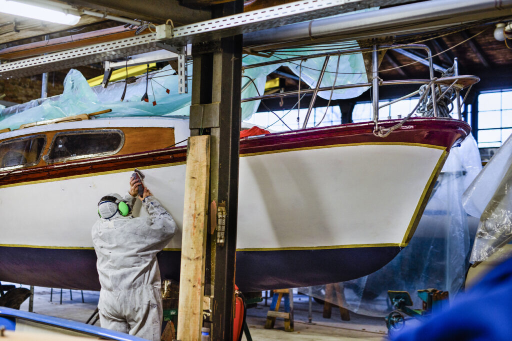 Marine technician sanding a yacht hull in a workshop